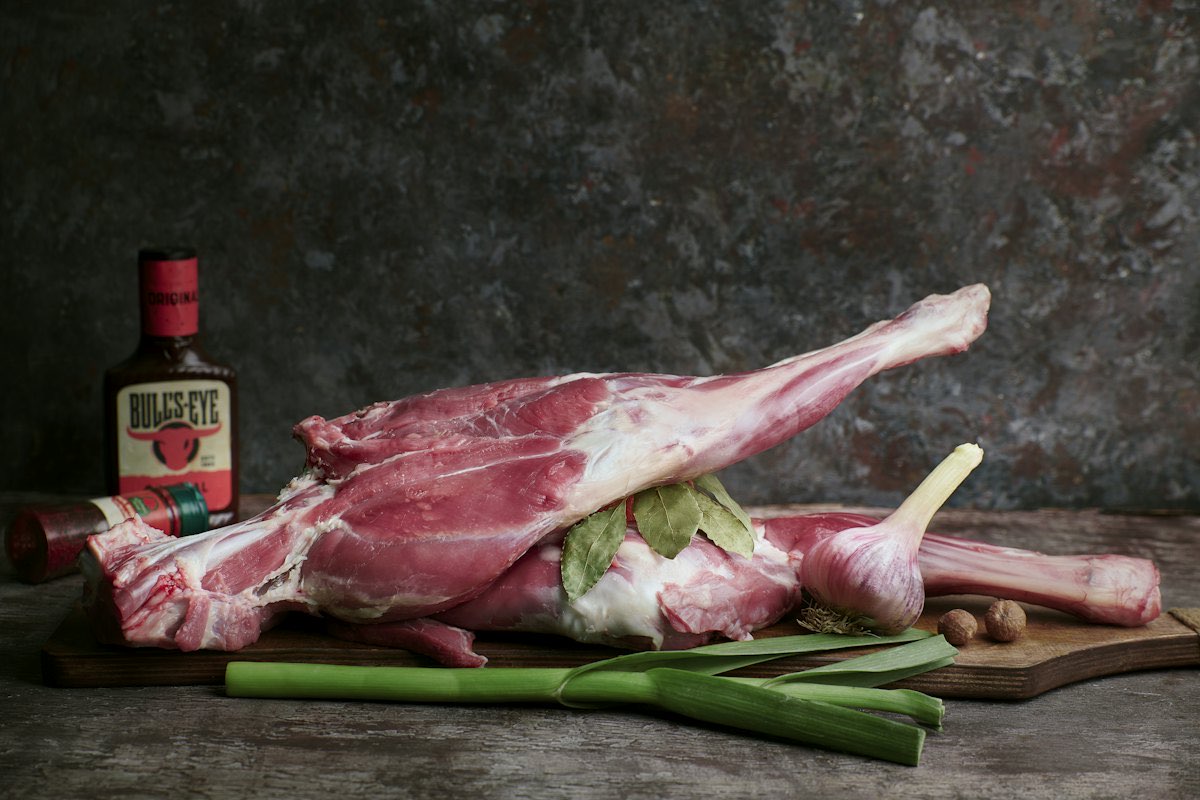 Raw leg of goat meat on a board